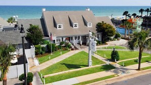 A coastal hotel with a large lawn, a flagpole, and a view of the ocean. - The Pink Flamingo | Bold & Vibrant By The Beach (Myrtle Beach)