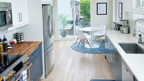 Una cocina moderna con armarios blancos, electrodomésticos de acero inoxidable y un ventanal grande.