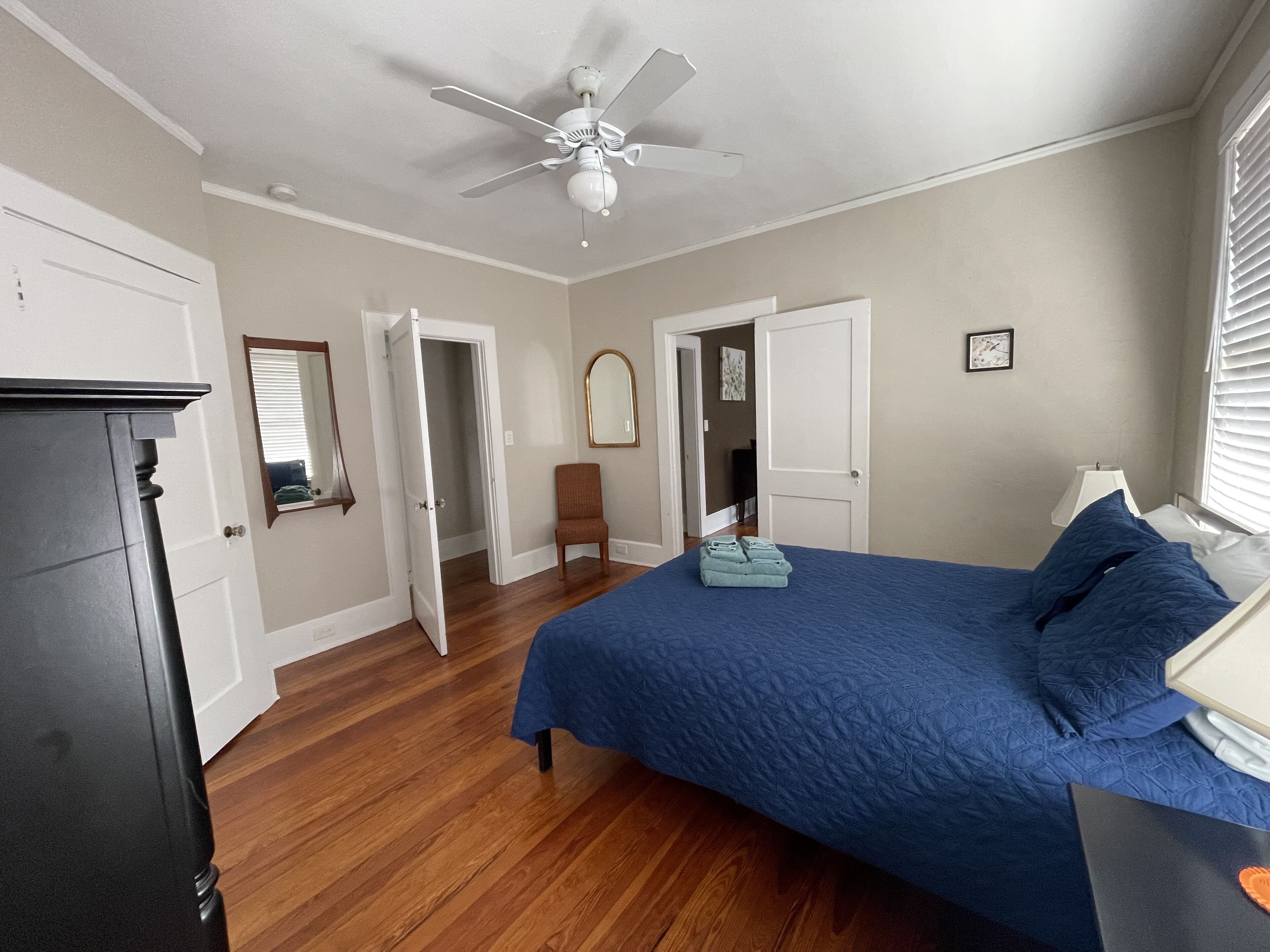 A bedroom with a bed, a chair, a dresser, and a ceiling fan.