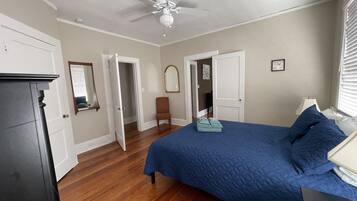 A bedroom with a bed, a chair, a dresser, and a ceiling fan.