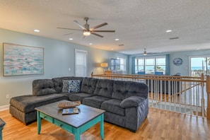 A living room with a sectional sofa, a coffee table, and a ceiling fan.