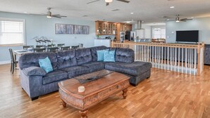 A spacious living room with a dark gray sectional sofa, a wooden coffee table, and a dining area with a white table and chairs. - Atlantic Blue (St. Augustine)