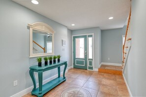 A hallway with a teal console table, a mirror, and a door with a green frame. - Atlantic Blue (St. Augustine)
