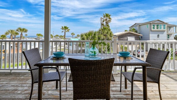 A covered outdoor seating area with a table and chairs, overlooking a residential neighborhood and the ocean. - Atlantic Blue (St. Augustine)