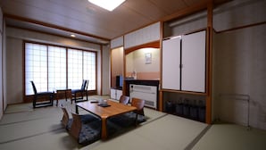 Una habitación japonesa tradicional con suelo de tatami, una mesa baja con cojines y puertas correderas.