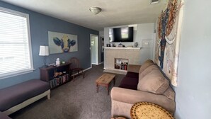 Uma sala de estar com sofá, mesa de centro, televisão e lareira.