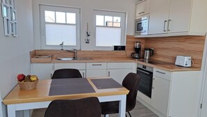 A compact kitchen with a dining area, featuring a sink, microwave, coffee maker, and toaster.