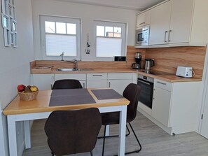 Ett kompakt kök med en matplats, utrustat med diskho, mikrovågsugn, kaffebryggare och brödrost.