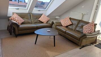 Eine moderne Loft-Wohnung mit einem braunen Ledersofa, einem runden Couchtisch und Kissen mit Muster.