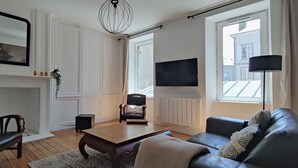 Ett vardagsrum med en öppen spis, en soffa, ett soffbord och en tv som är monterad på väggen.