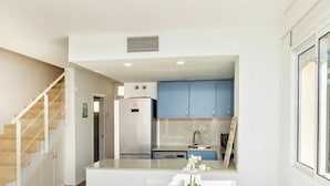 A modern kitchen with blue cabinets, a stainless steel refrigerator, and a dining area with a white table and chairs. - Wonderful  villa for 6 guests with pool, A/C, WIFI, TV and terrace (L'escala)