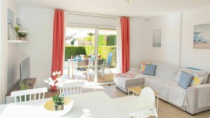 A bright living room with a sofa, a dining table, and a sliding glass door leading to a patio. - Wonderful  villa for 6 guests with pool, A/C, WIFI, TV and terrace (L'escala)
