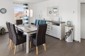 Un espace repas moderne avec une table en bois, des chaises noires et un meuble blanc avec des tiroirs.