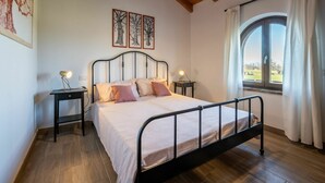 A bedroom with a bed, two bedside tables, a window with curtains, and wooden flooring. - Nice apartment for 3 guests with WIFI, TV, patio and pets allowed (Mondovì)