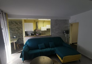 A living room with a teal sofa, a yellow coffee table, and a stone accent wall.