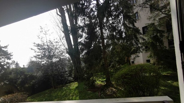 Een balkon met uitzicht op een gebouw en bomen.