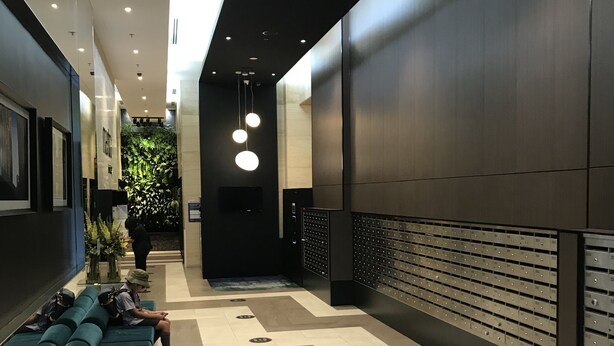 En modern hotellobby med en lång receptionsdisk, en sittgrupp med soffor och ett väggmonterat bagageförvaringsskåp.