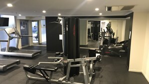 Ett gym med löpband, styrketräningsmaskiner och speglar.