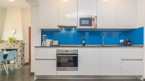 Eine moderne Küche mit weißen Schränken, einer eingebauten Mikrowelle, einem Toaster und einer Kaffeemaschine.