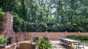 An outdoor patio with brick walls, wicker furniture, and potted plants.