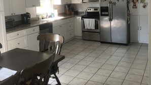 A kitchen with white cabinets, a microwave, a stove, a refrigerator, and a ceiling fan. - Your Penn State Destination (State College)