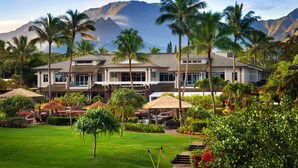 A resort with a large building, multiple palm trees, and a mountainous backdrop.