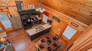 A wooden cabin interior with a kitchen, dining area, and a cozy living space.