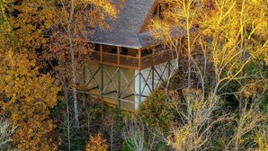 A wooden cabin with a balcony, surrounded by autumn-colored trees.
