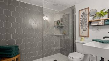 Een bad/douchecombinatie, een haardroger, handdoeken, toiletpapier