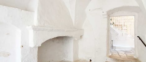 A white-walled corridor with a stone staircase leading to a door.