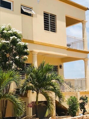 Stunning standalone building with a central balcony and lush green surroundings.