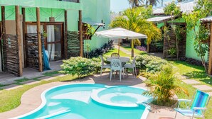 A pool area with a circular design, surrounded by a patio with a table and chairs.