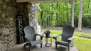 A porch with two Adirondack chairs, a stone wall, and a welcome sign. - 8 bed Lodge Near Camelback/Outlets-HOT TUB (Tannersville)