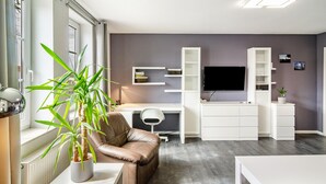 Una sala de estar moderna con un sofá de cuero, un escritorio blanco, un televisor de pantalla plana y estanterías empotradas.