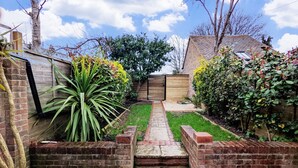 Un jardín con un sendero de ladrillo que conduce a una puerta de madera.