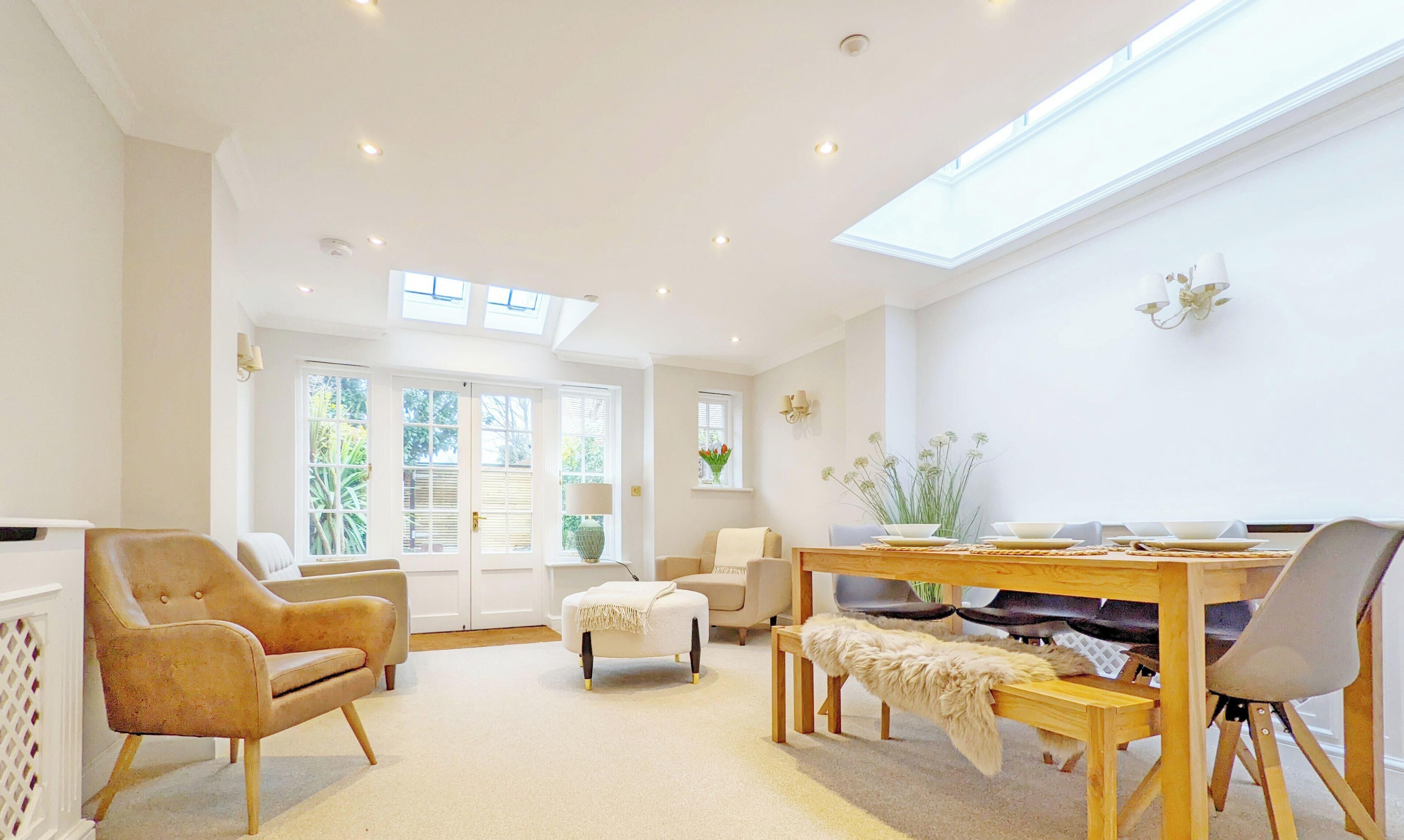 A spacious living room with a dining area, large windows, and a high ceiling.