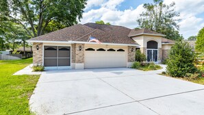A two-story house with a garage, a front porch, and a landscaped yard. - Cozy retreat in Spring Hill, 3 beds, 3 baths w/heated Pool  and Hot Tub (Spring Hill)