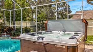 A hot tub with a control panel, surrounded by a pool and greenery, enclosed by a glass structure. - Cozy retreat in Spring Hill, 3 beds, 3 baths w/heated Pool  and Hot Tub (Spring Hill)
