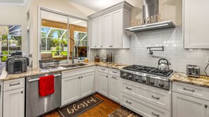A modern kitchen with white cabinets, a stainless steel stove, and a large window offering a view of the outdoors. - Cozy retreat in Spring Hill, 3 beds, 3 baths w/heated Pool  and Hot Tub (Spring Hill)