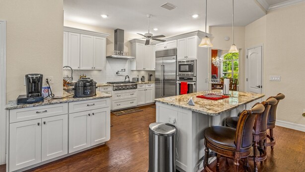 A spacious kitchen with white cabinets, a large island with bar stools, stainless steel appliances, and a ceiling fan. - Cozy retreat in Spring Hill, 3 beds, 3 baths w/heated Pool  and Hot Tub (Spring Hill)