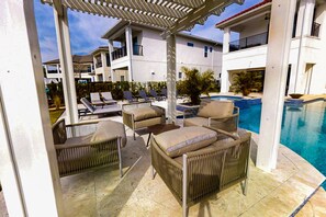 Ein Poolbereich mit Korlounge-Stühlen, einem kleinen Tisch und einem Pool.