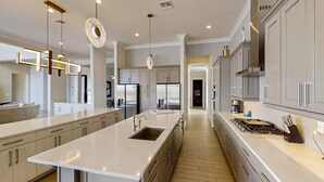A modern kitchen with a large island, stainless steel appliances, and pendant lighting. - Luxurious Oasis with Immersive Circus Bedroom at Reunion (Kissimmee)