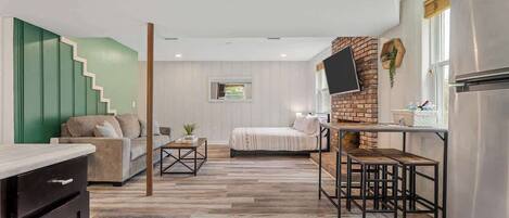 A modern interior with a kitchen area, a dining table with benches, a sofa, and a staircase.