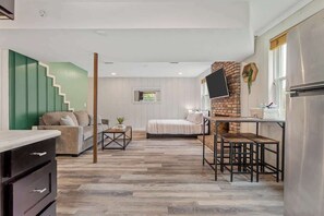 A modern interior with a kitchen area, a dining table with benches, a sofa, and a staircase.