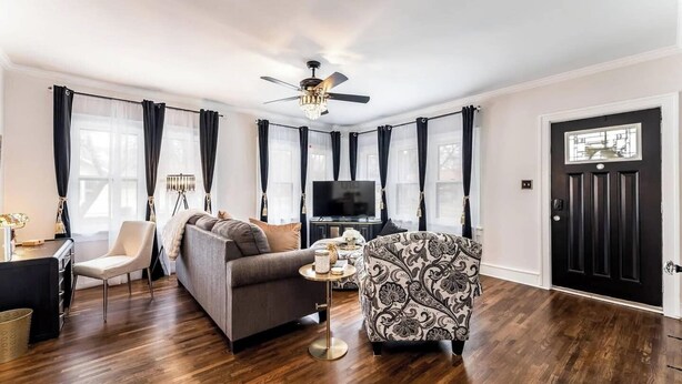 A modern living room with a sofa, armchair, TV, and a ceiling fan. - Roaring Riverside - Art Deco Luxe - 2 Kings! (Wichita)
