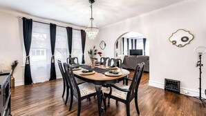 A dining area with a round table, black chairs, and a chandelier. - Roaring Riverside - Art Deco Luxe - 2 Kings! (Wichita)