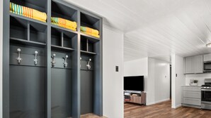 A modern living room with a built-in bench, grey shelving, and a flat-screen TV. - Pleasure Point Place WATERFRONT Cottage (Florien)