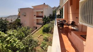 Ein Wohngebäude mit Balkon, Sitzgelegenheit im Freien und Blick auf die Stadtlandschaft.