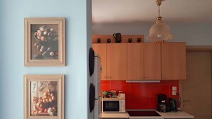 Eine Küche mit Holzausstattung, einer Mikrowelle, einem Herd und zwei gerahmten Bildern an der Wand.