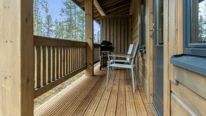 Een houten terras met een hekwerk, een barbecue en twee stoelen.